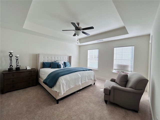 bedroom with carpet flooring, a raised ceiling, and ceiling fan