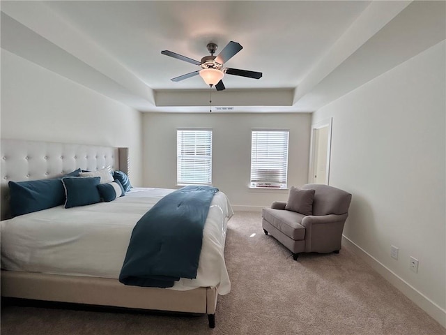 carpeted bedroom featuring a raised ceiling and ceiling fan