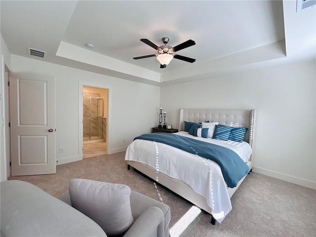 carpeted bedroom featuring ceiling fan, a raised ceiling, and ensuite bathroom