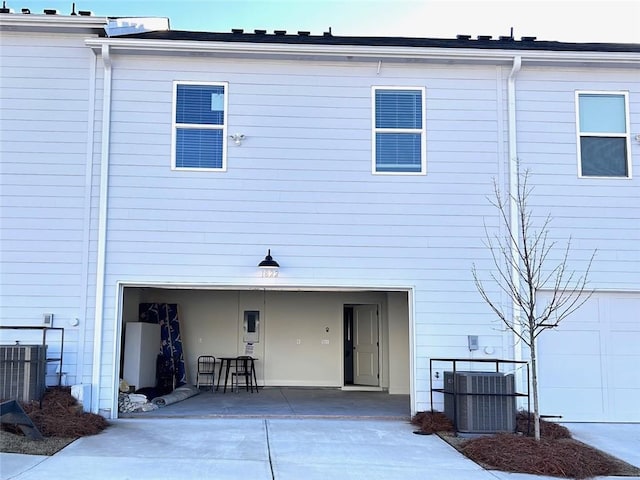 back of property featuring central AC unit and a garage