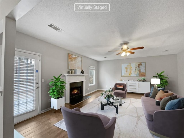 living room with a healthy amount of sunlight, ceiling fan, a textured ceiling, and hardwood / wood-style flooring