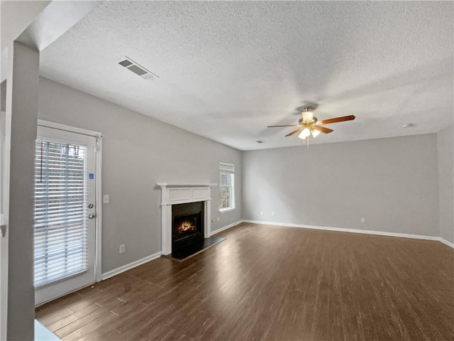 unfurnished living room with a healthy amount of sunlight, ceiling fan, a textured ceiling, and dark hardwood / wood-style floors