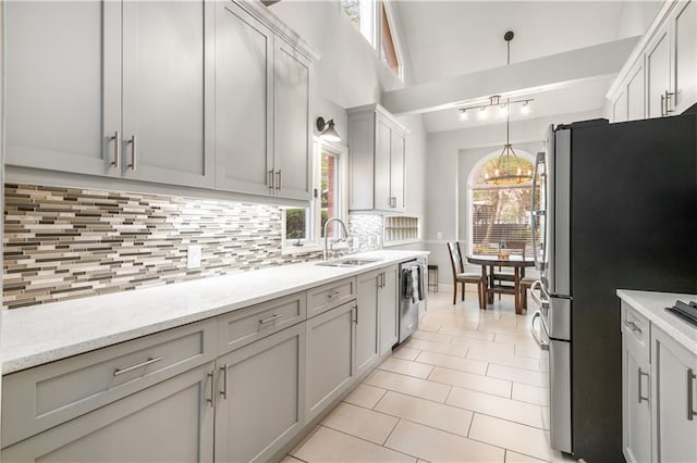 kitchen with pendant lighting, a sink, tasteful backsplash, stainless steel appliances, and light tile patterned floors