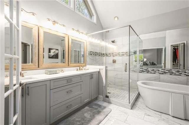 bathroom featuring a shower stall, vaulted ceiling, double vanity, a soaking tub, and marble finish floor