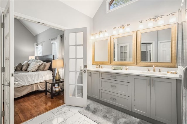 bathroom with vaulted ceiling, marble finish floor, connected bathroom, and a sink