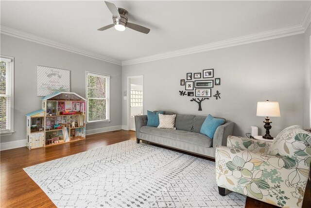 living area with crown molding, plenty of natural light, wood finished floors, and baseboards