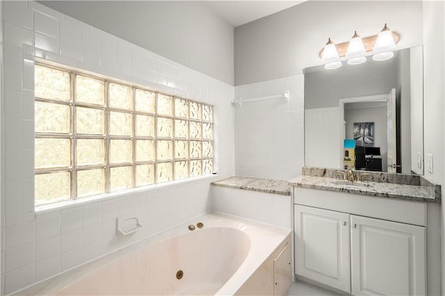 full bath featuring a jetted tub, vanity, a healthy amount of sunlight, and ensuite bathroom