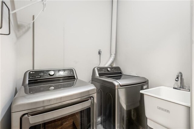 laundry area with laundry area, separate washer and dryer, and a sink