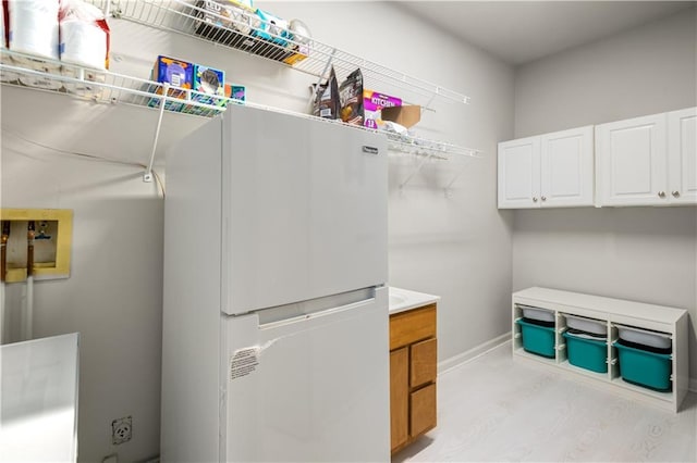 clothes washing area with washer hookup, light wood-style flooring, and baseboards