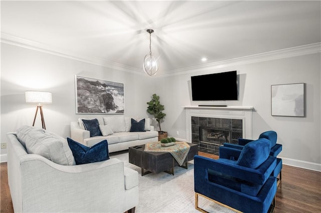 living area with a tiled fireplace, crown molding, baseboards, and wood finished floors