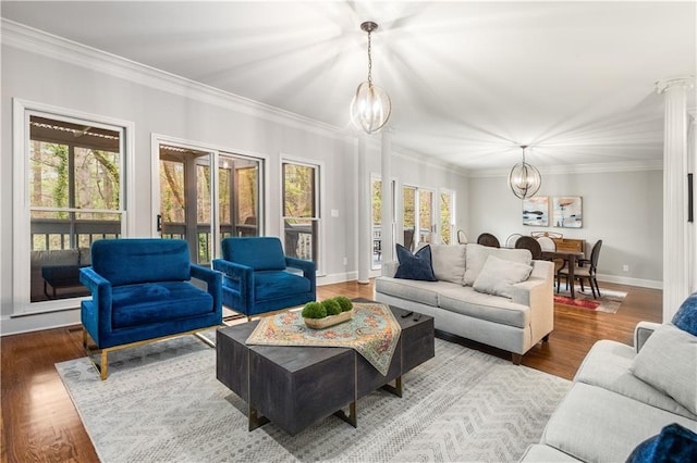 living area featuring baseboards, an inviting chandelier, wood finished floors, and crown molding