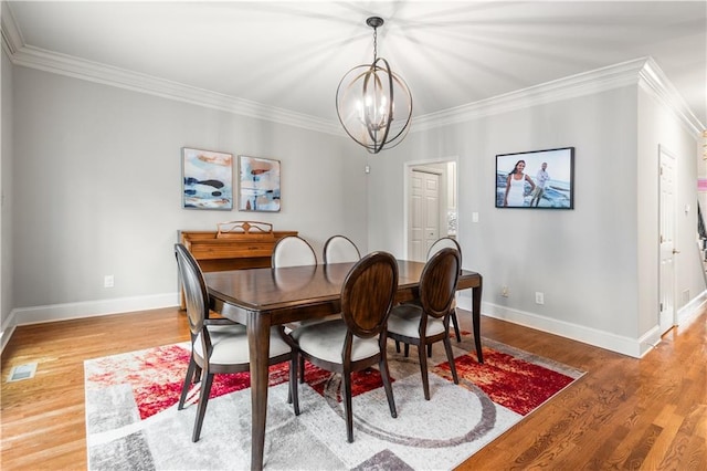 dining room with wood finished floors, a chandelier, and ornamental molding