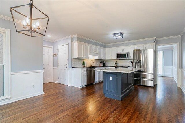 kitchen featuring an inviting chandelier, crown molding, dark wood-style flooring, white cabinets, and stainless steel appliances