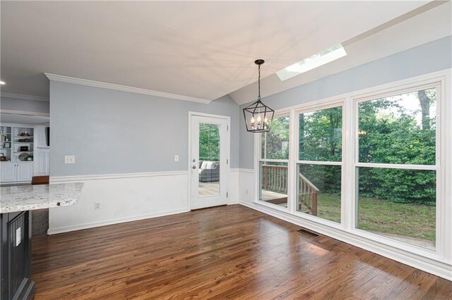 unfurnished dining area with visible vents, crown molding, wainscoting, dark wood finished floors, and an inviting chandelier