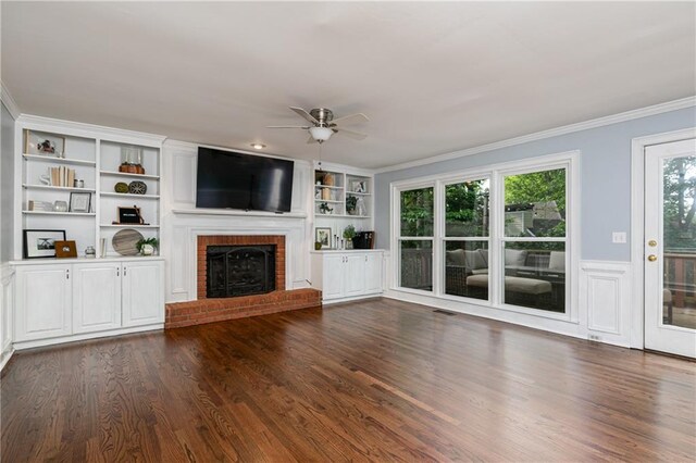 unfurnished living room featuring crown molding, dark wood-type flooring, ceiling fan, and a fireplace
