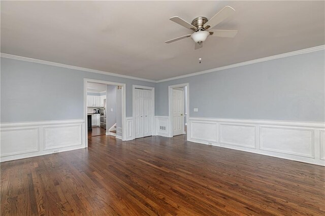 spare room featuring crown molding, a ceiling fan, a decorative wall, and a wainscoted wall