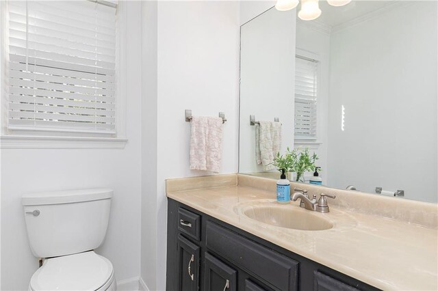 bathroom with vanity, ornamental molding, baseboards, and toilet