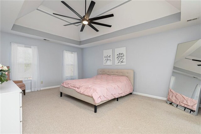 carpeted bedroom with baseboards, a tray ceiling, and visible vents