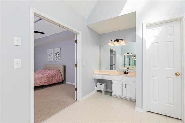 bathroom with baseboards, vanity, and lofted ceiling