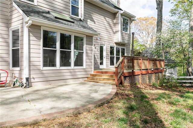rear view of house featuring a patio, fence, roof with shingles, and a deck