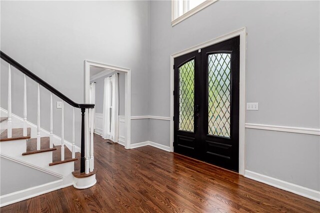 foyer featuring french doors, wood finished floors, baseboards, a high ceiling, and stairs