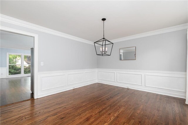unfurnished room with an inviting chandelier, a wainscoted wall, crown molding, and dark wood-style floors