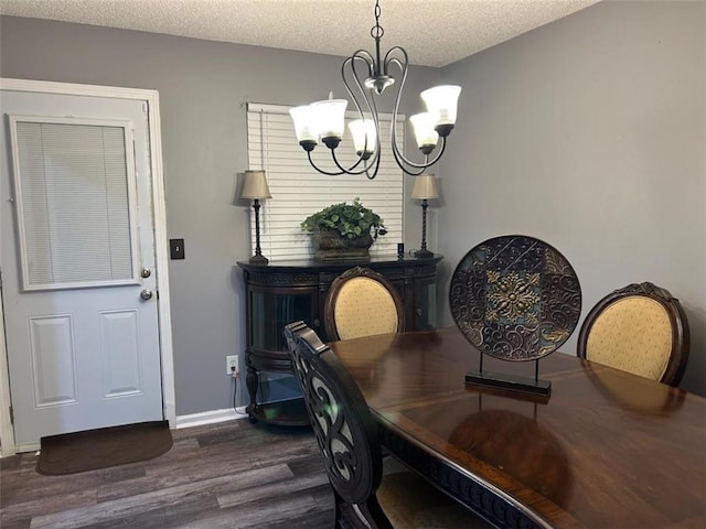 dining area featuring a chandelier, dark wood finished floors, a textured ceiling, and baseboards