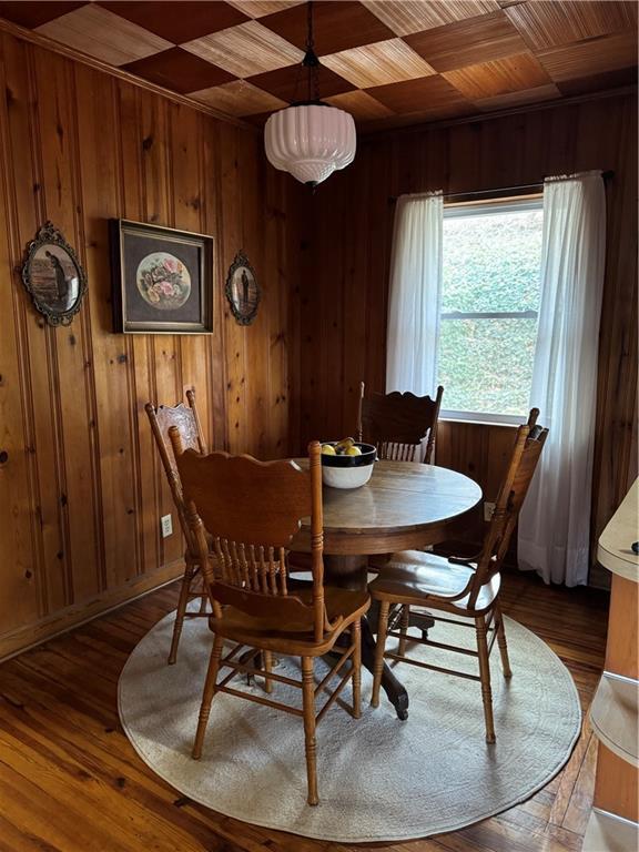 dining space with wood walls, wooden ceiling, and wood finished floors