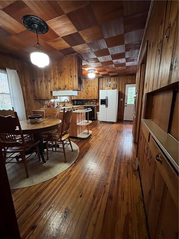 dining space with wood ceiling, wooden walls, and hardwood / wood-style floors