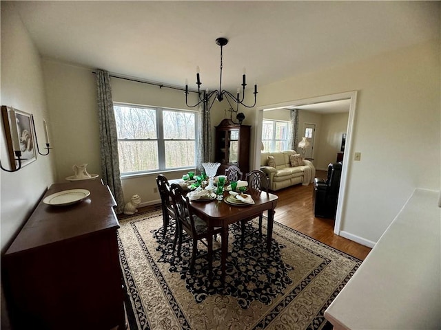 dining space featuring an inviting chandelier, baseboards, plenty of natural light, and light wood finished floors
