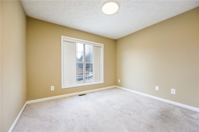 spare room with baseboards, a textured ceiling, visible vents, and carpet flooring