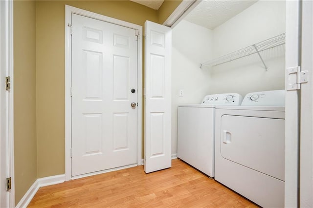 washroom featuring baseboards, laundry area, washer and clothes dryer, and light wood-style floors