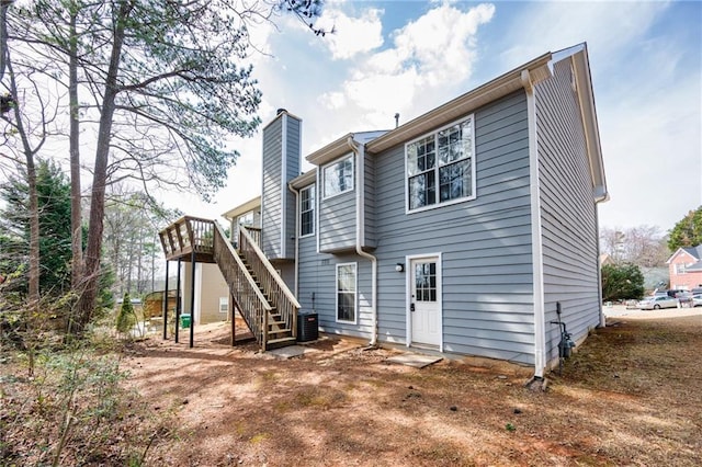 back of property with cooling unit, a chimney, stairway, and a wooden deck