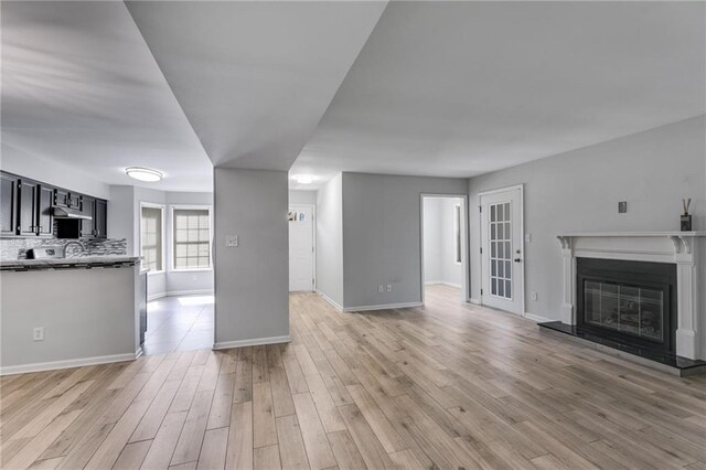 2135 N Forest Trl, Dunwoody, GA 30338 - unfurnished living room featuring light wood-style floors, baseboards, a glass covered fireplace, and a sink