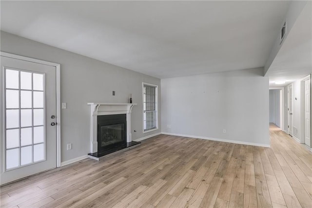 2135 N Forest Trl, Dunwoody, GA 30338 - unfurnished living room featuring light wood-type flooring, a glass covered fireplace, baseboards, and healthy amount of natural light