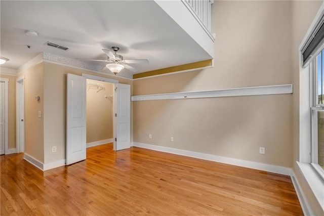 unfurnished bedroom featuring crown molding, light hardwood / wood-style floors, a closet, and ceiling fan