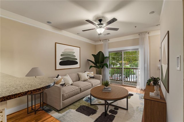 living room featuring crown molding, light hardwood / wood-style floors, and ceiling fan