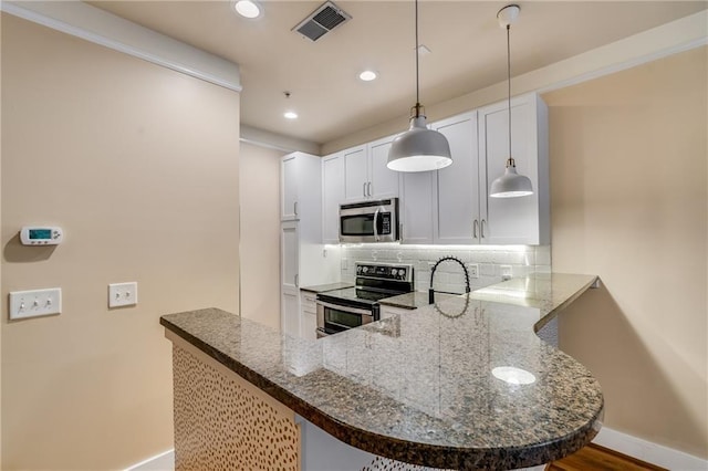 kitchen featuring pendant lighting, stainless steel appliances, tasteful backsplash, white cabinets, and kitchen peninsula