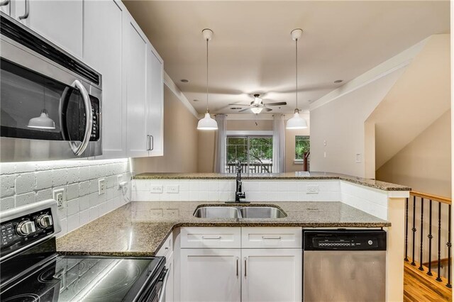 kitchen with pendant lighting, sink, appliances with stainless steel finishes, white cabinetry, and dark stone counters