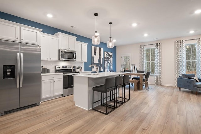 104 Chapel Hill Pkwy, Newnan, GA 30263 - kitchen with a sink, a kitchen breakfast bar, light wood-style floors, stainless steel appliances, and white cabinets