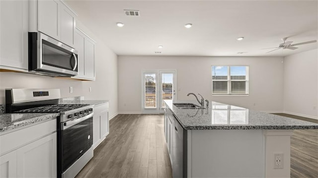 1316 Village Brook Dr, Dacula, GA 30019 - kitchen featuring stainless steel appliances, wood finished floors, a kitchen island with sink, light stone counters, and white cabinetry