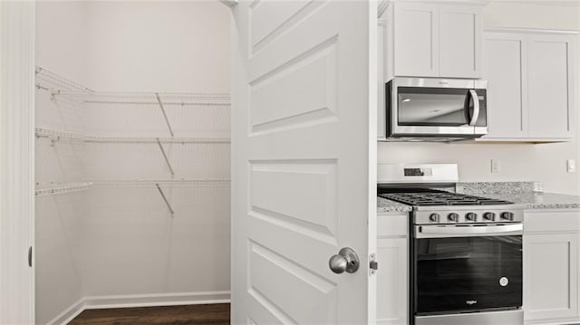 1316 Village Brook Dr, Dacula, GA 30019 - kitchen with appliances with stainless steel finishes, white cabinets, dark wood finished floors, and light stone counters