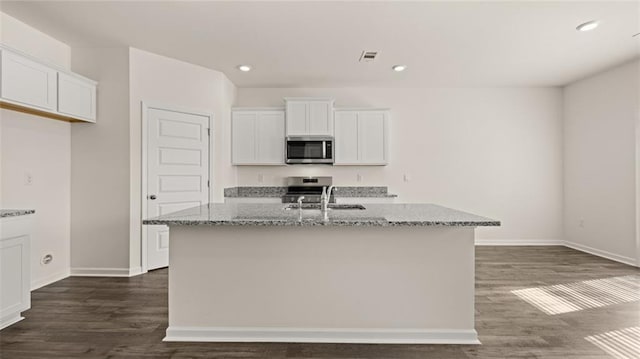 1316 Village Brook Dr, Dacula, GA 30019 - kitchen with appliances with stainless steel finishes, white cabinetry, light stone countertops, dark wood-style floors, and an island with sink