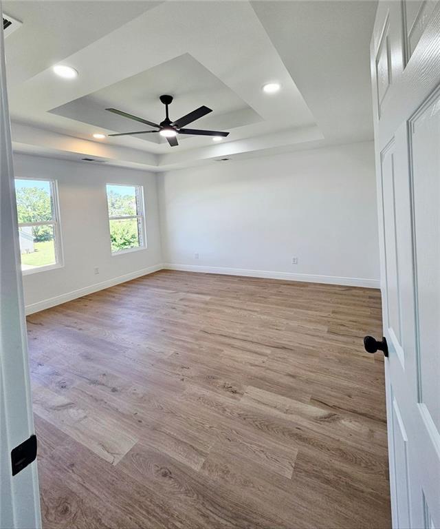 681 Burtons Cv, Hampton, GA 30228 - empty room with a tray ceiling, ceiling fan, wood finished floors, baseboards, and recessed lighting