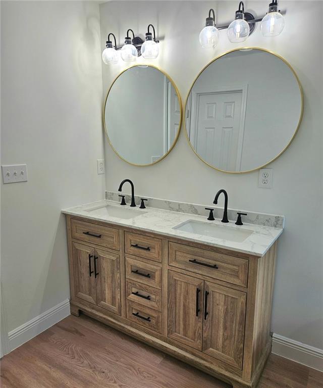 681 Burtons Cv, Hampton, GA 30228 - bathroom featuring double vanity, wood finished floors, and baseboards