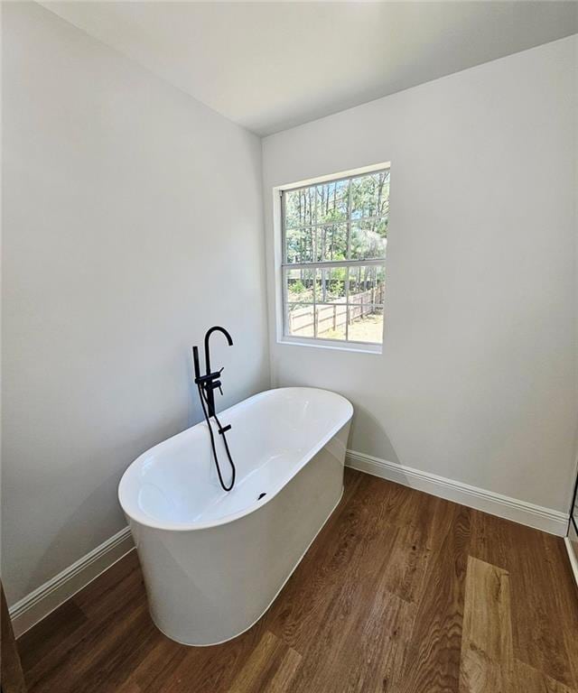 681 Burtons Cv, Hampton, GA 30228 - bathroom featuring wood finished floors, baseboards, and a soaking tub