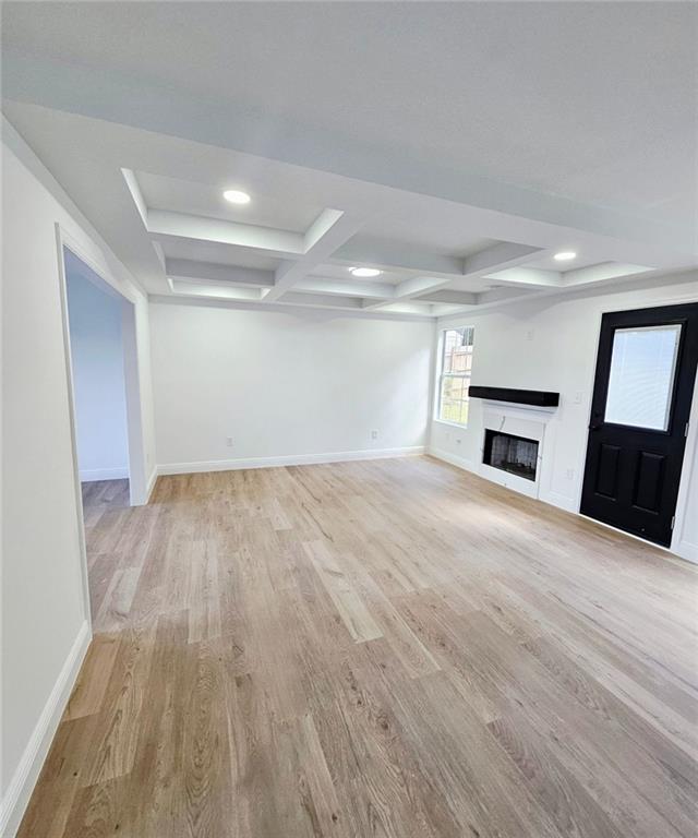 681 Burtons Cv, Hampton, GA 30228 - unfurnished living room featuring light wood-style floors, baseboards, coffered ceiling, a fireplace, and beam ceiling