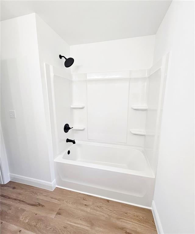 681 Burtons Cv, Hampton, GA 30228 - bathroom with wood finished floors, baseboards, and bathtub / shower combination