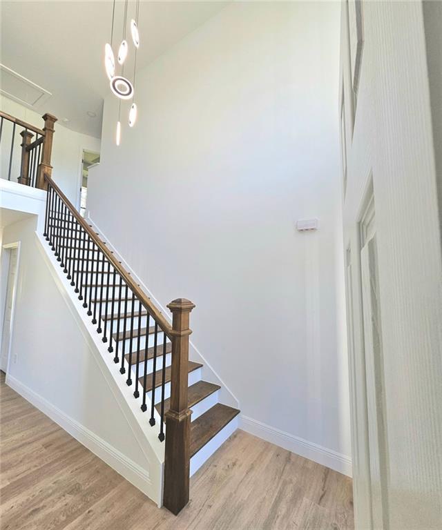 681 Burtons Cv, Hampton, GA 30228 - stairway featuring wood finished floors, baseboards, and a towering ceiling