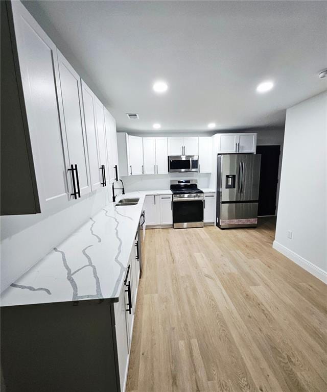 681 Burtons Cv, Hampton, GA 30228 - kitchen featuring stainless steel appliances, a sink, light wood-style floors, light stone countertops, and white cabinets